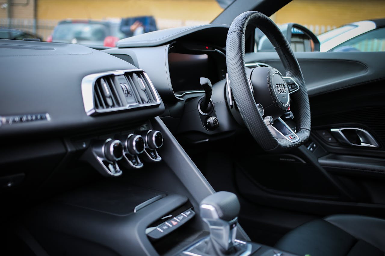 Explore the sleek interior of a modern luxury Audi, featuring a detailed view of the steering wheel and dashboard.